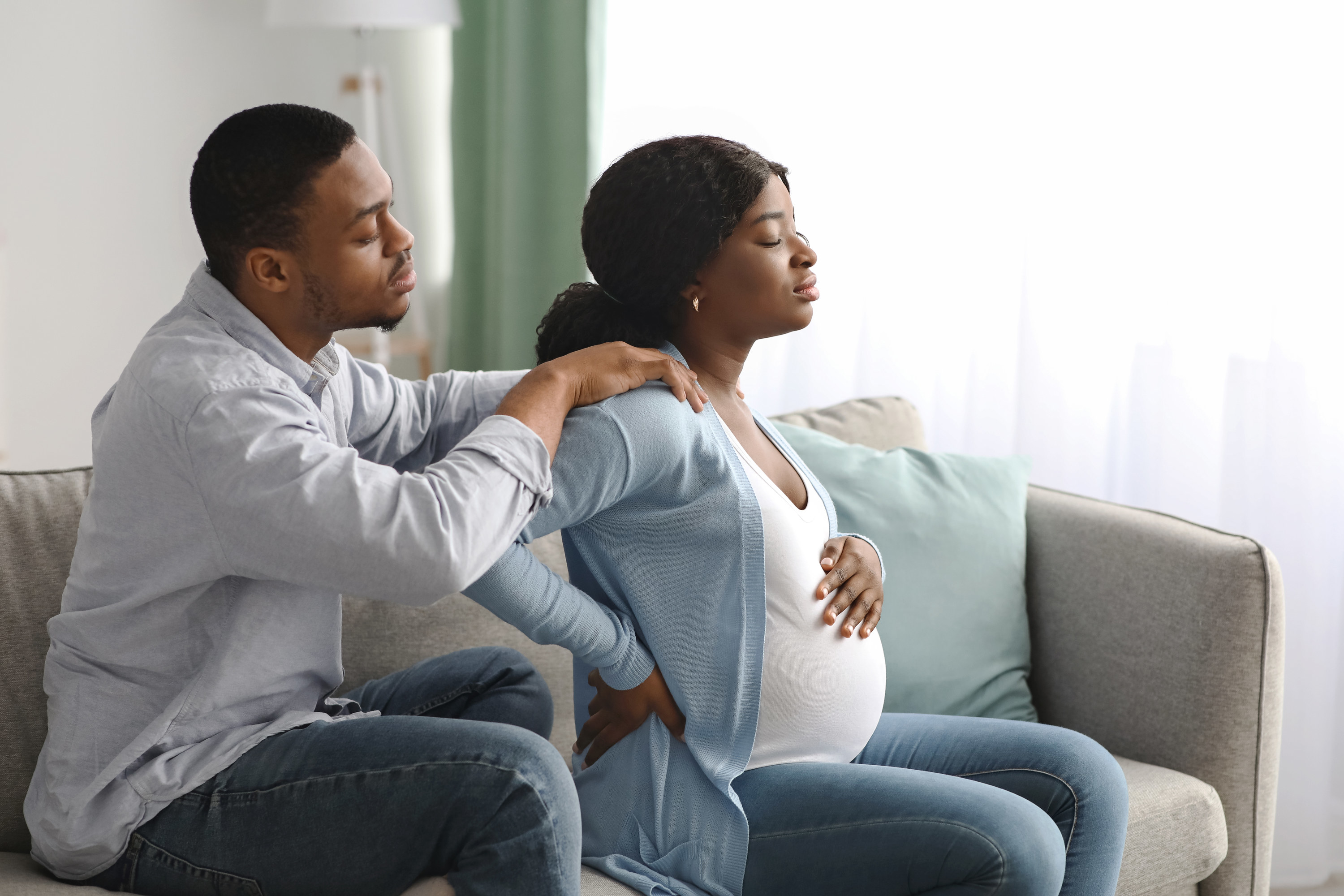 A man massaging his pregnant wife&#x27;s shoulders