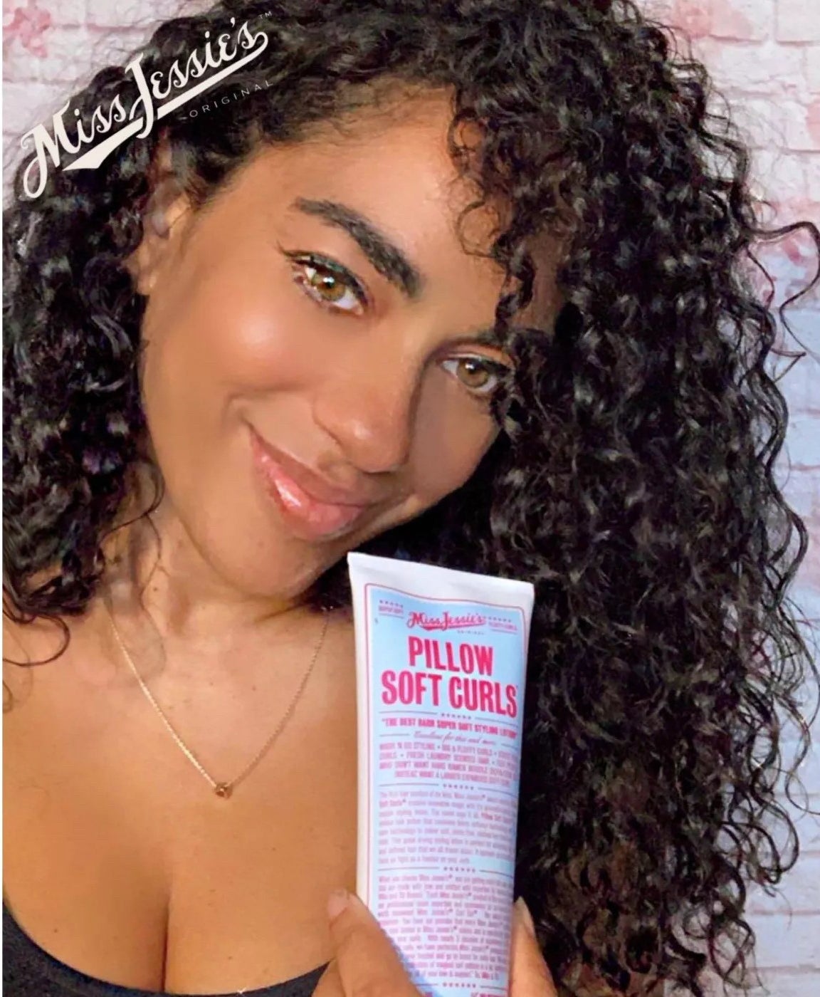 Model holding the tube of styling lotion next to their curly hair