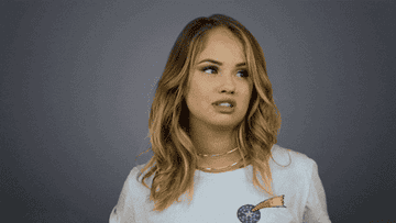 Debby Ryan saying seriously in front of a gray backdrop