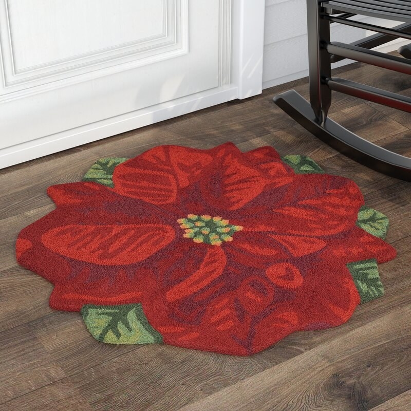 Red poinsettia area rug on wood floor