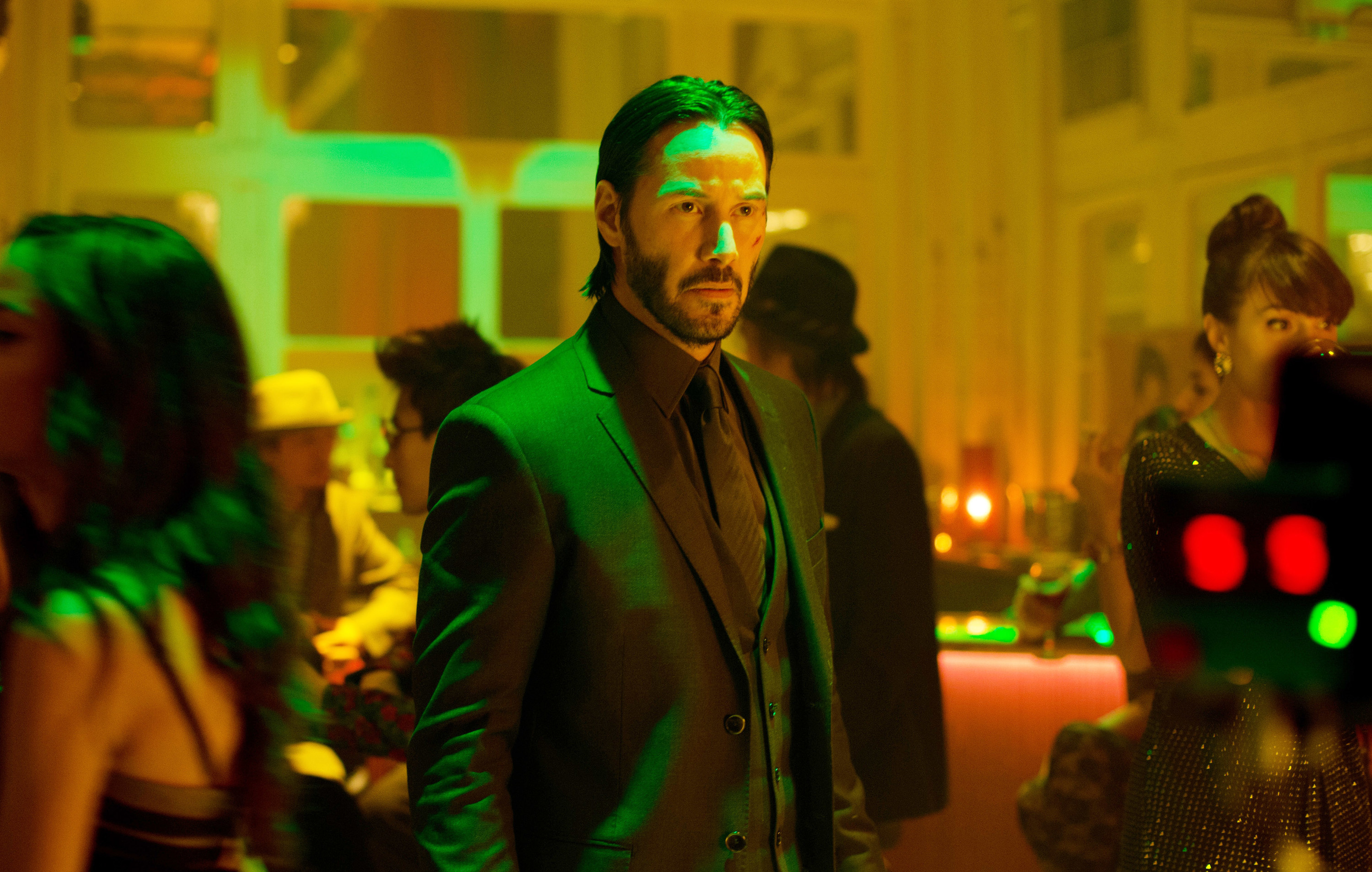 Keanu Reeves, in a suit, as John Wick, walking through a bar