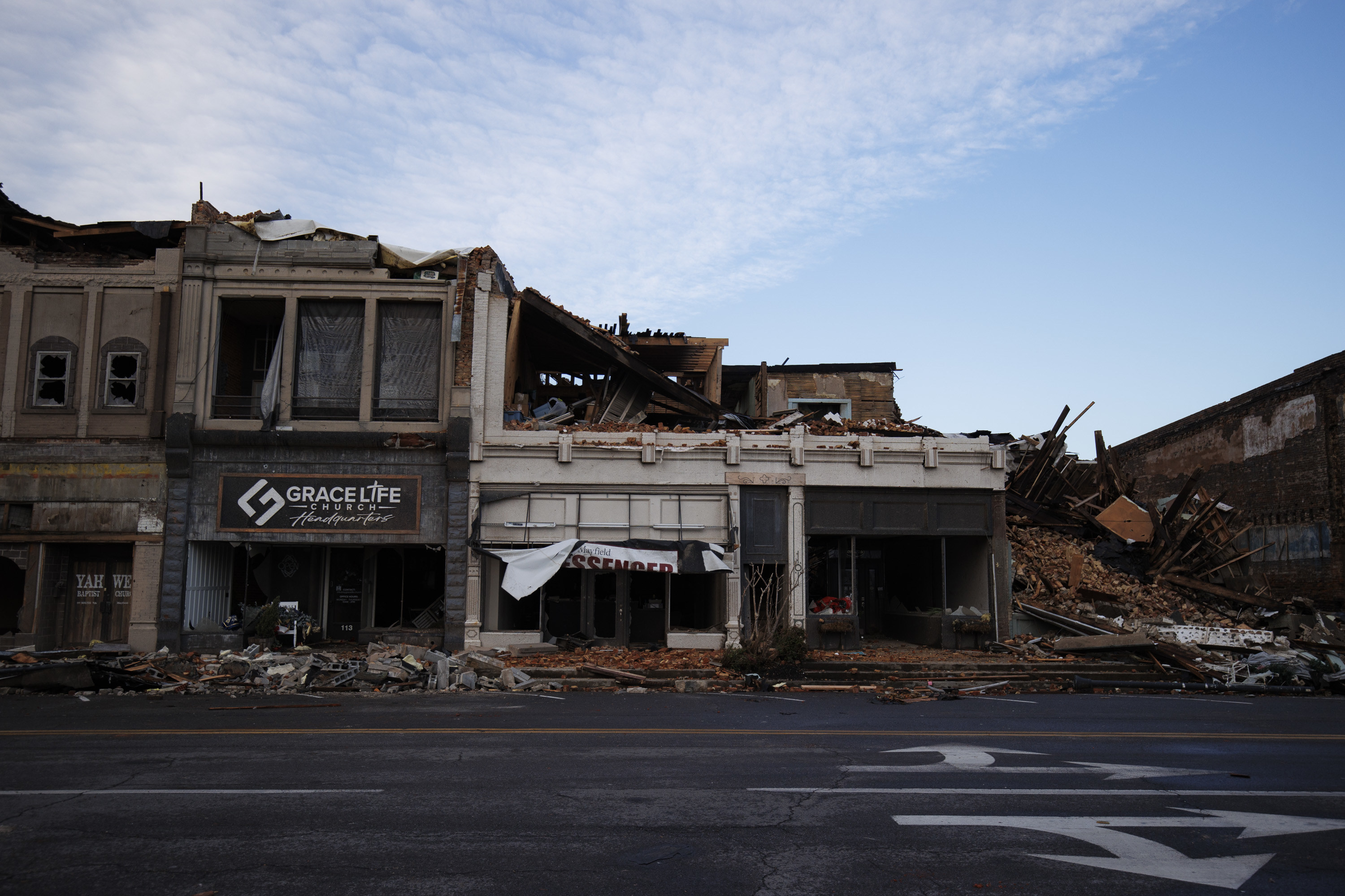 Empty storefronts, some damaged, next to a razed building