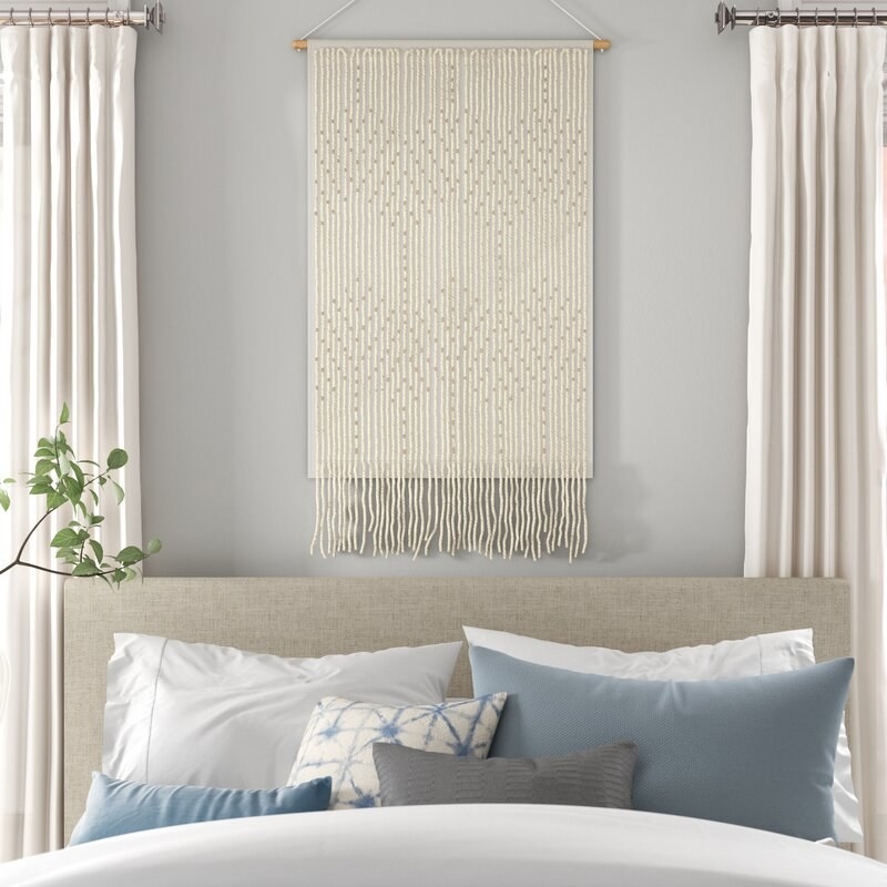 A image of a cotton hanging tapestry over a bed