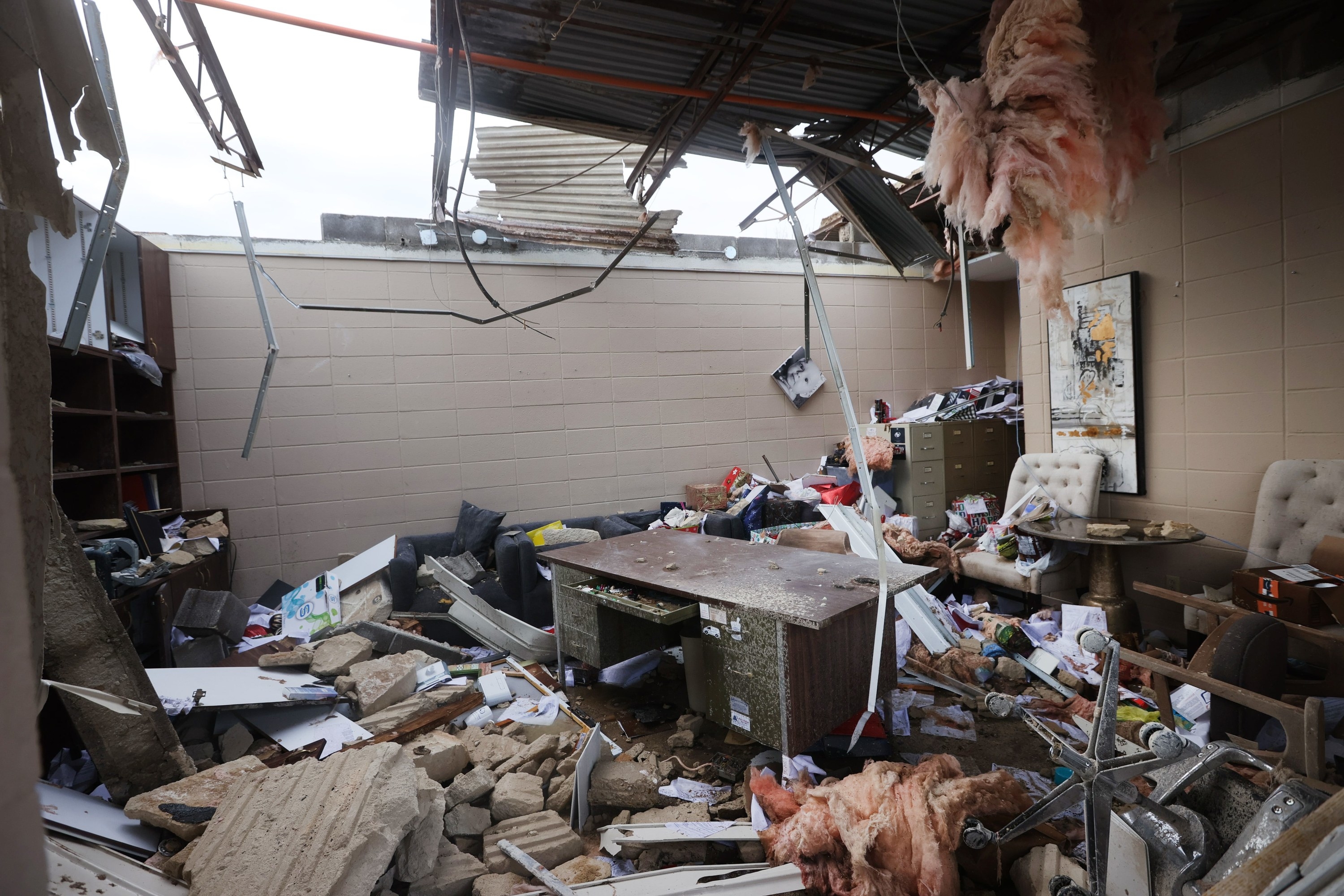 A desk sits amid debris below a collapsed roof