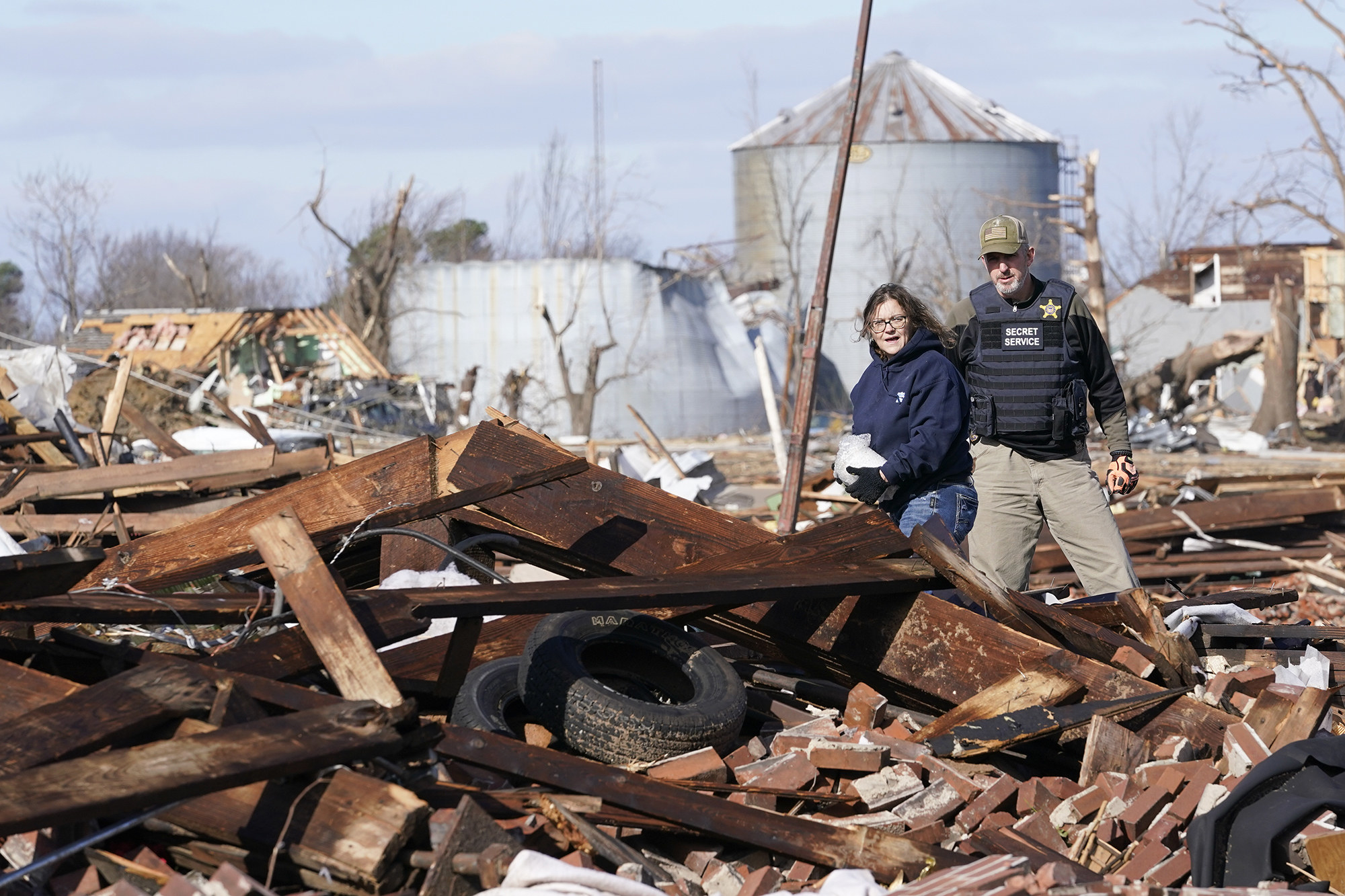 A man and a woman stand amid a scene of rubble