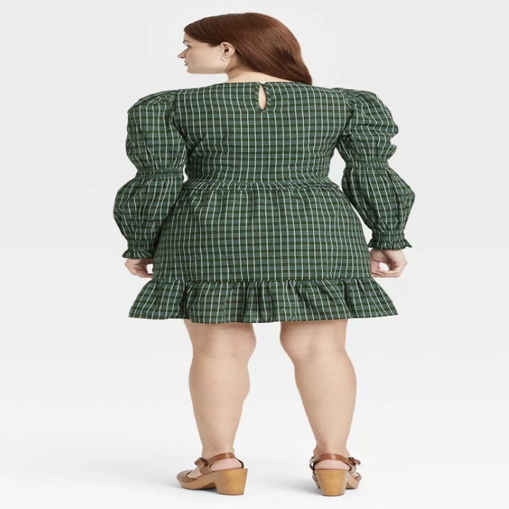 back view of model wearing the dress in a green plaid pattern