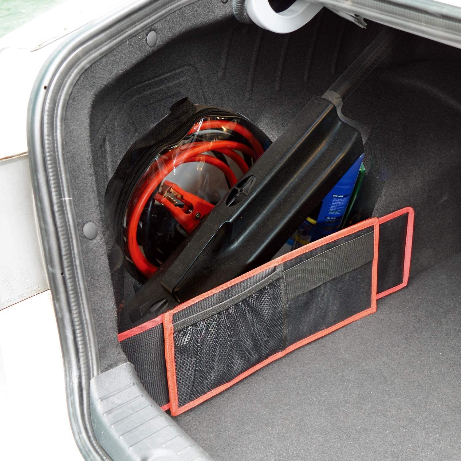 The storage wall in black with orange accents holding objects behind it against the trunk wall of a car