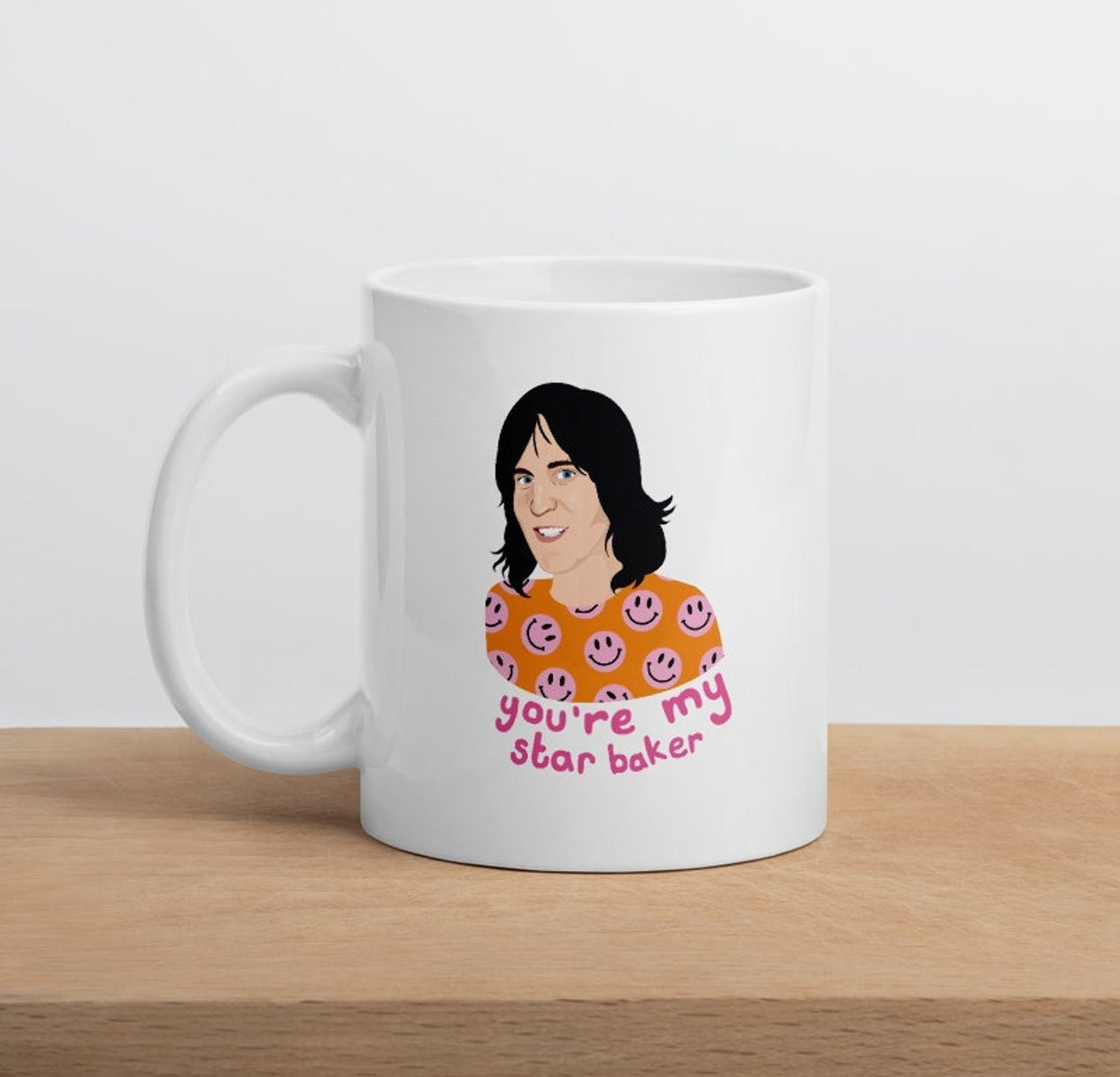 A white mug with an illustration of Noel Fielding in an orange and pink smiley face shirt with text: you&#x27;re my star baker