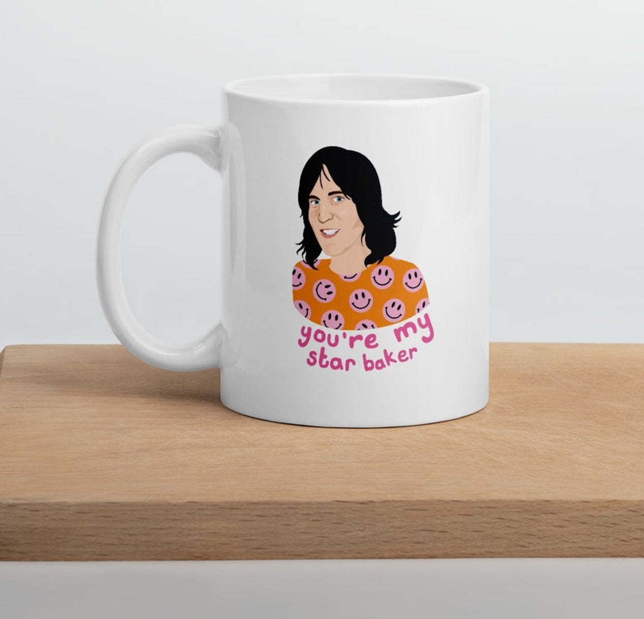 A white mug with an illustration of Noel Fielding in an orange and pink smiley face shirt with text: you&#x27;re my star baker