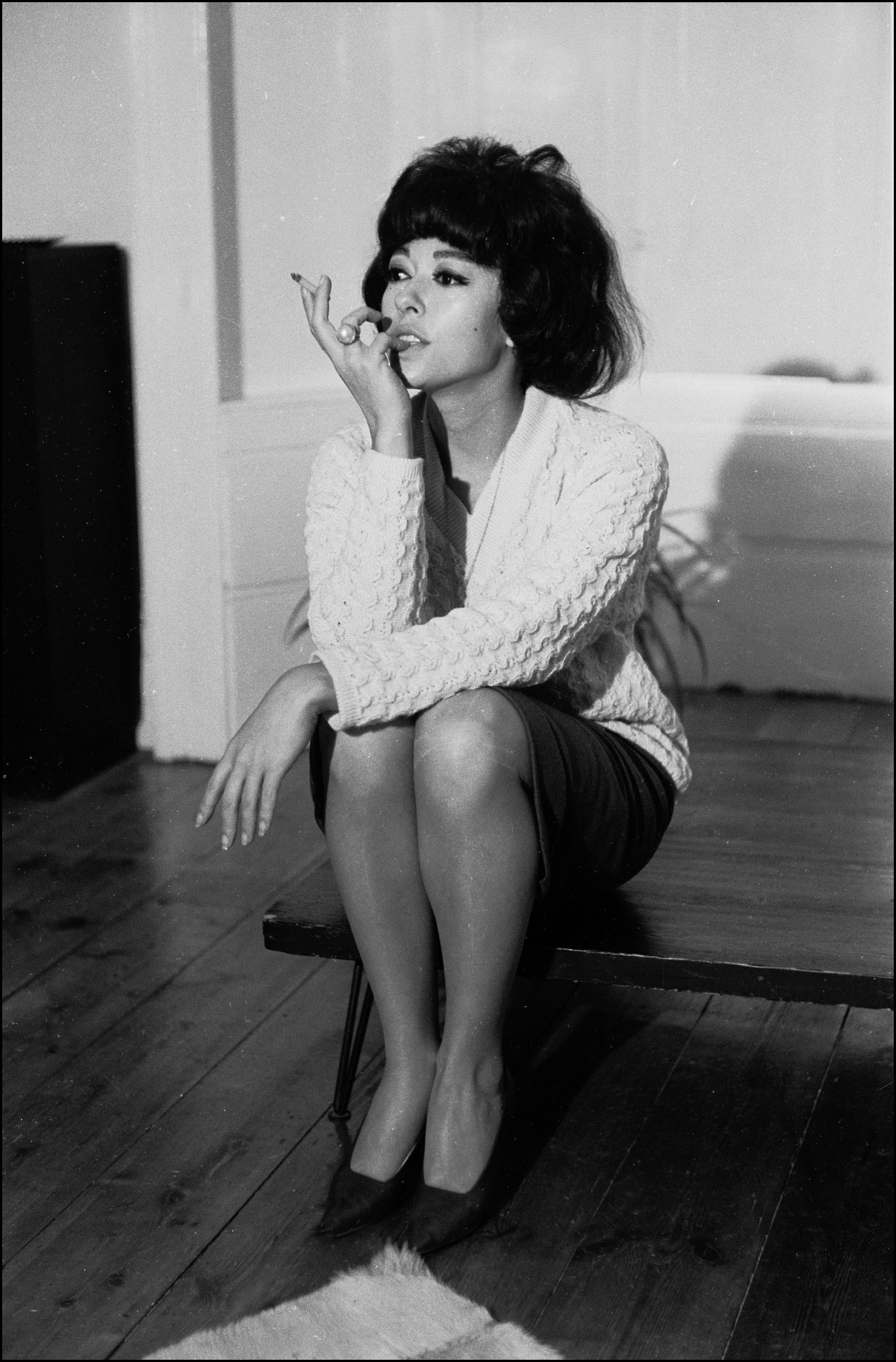 Rita sitting on a table holding a cigarette