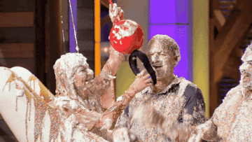 gif of contestants on master chef making a human banana split with a person putting a giant cherry headband on