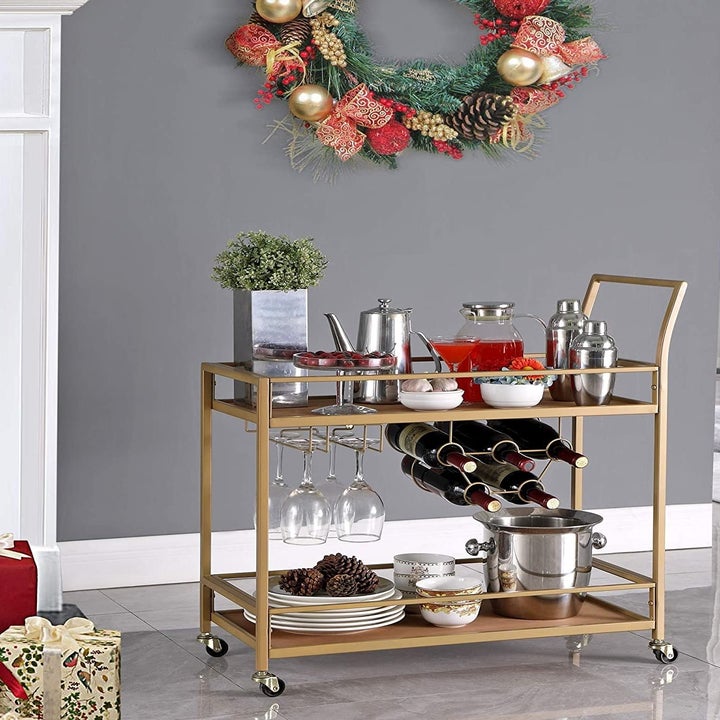The gold bar cart filled with drink ware in a festively decorated room