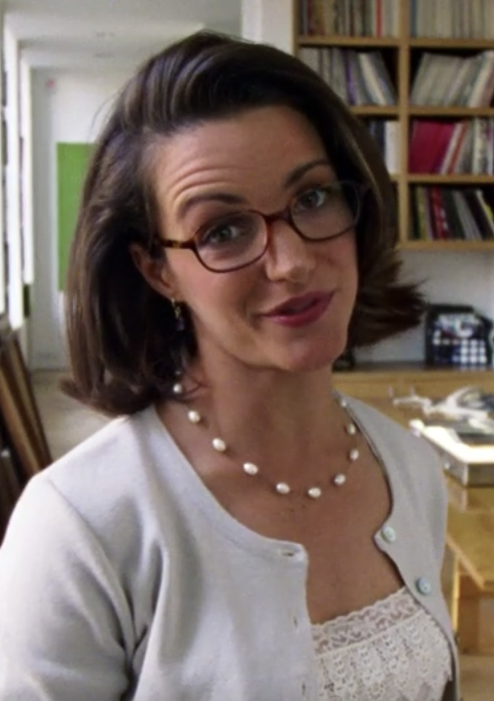 Davis wearing glasses, pearls, and a sweater in the pilot episode