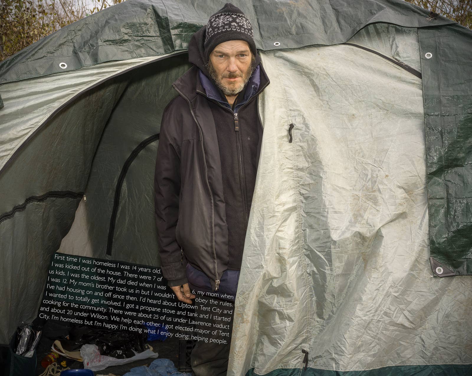 A man standing in tent while a paragraph of text is pasted over him, reading his experience becoming homeless and being elected "mayor of Tent City"