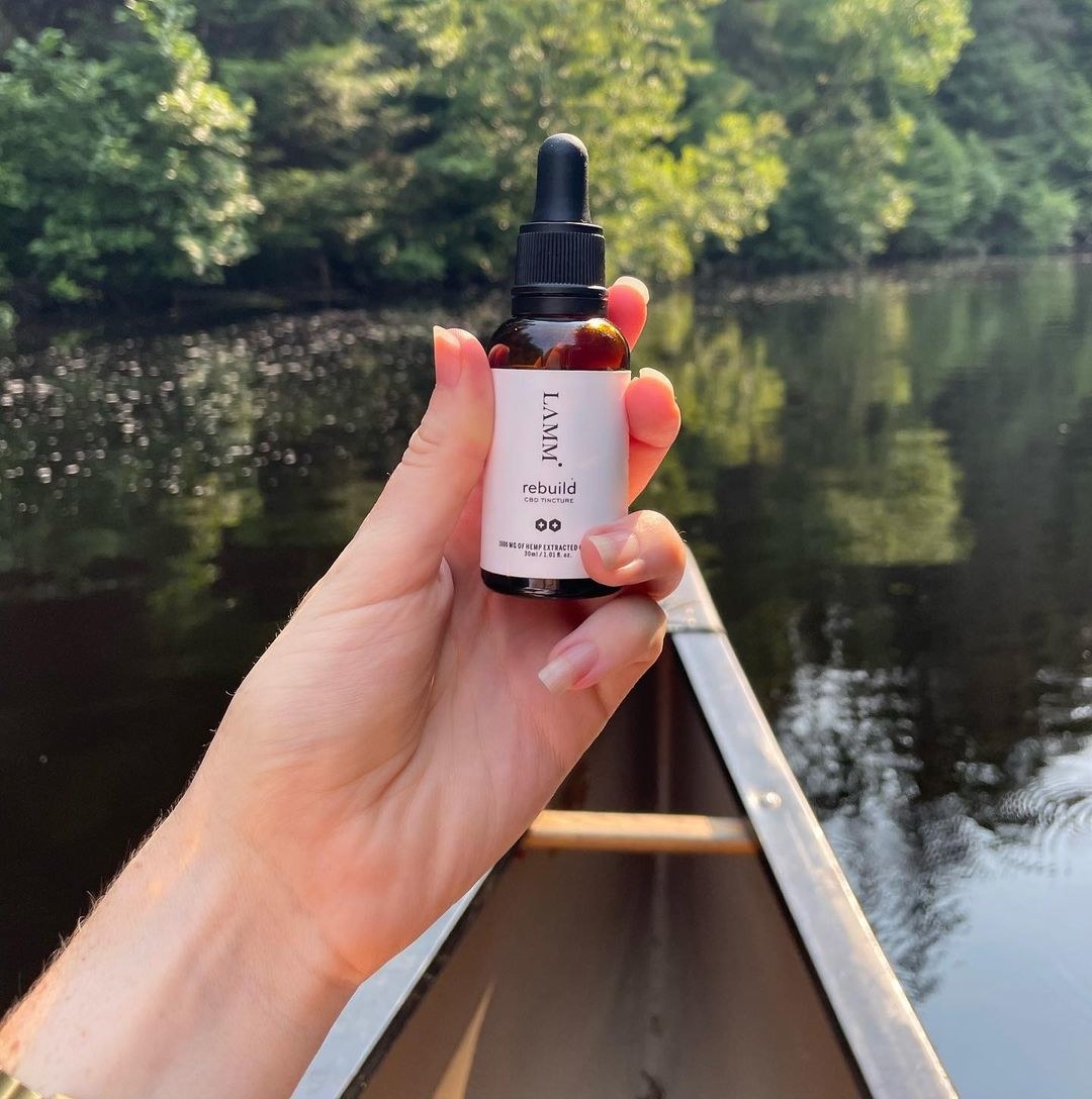 person in a canoe holding a tincture bottle