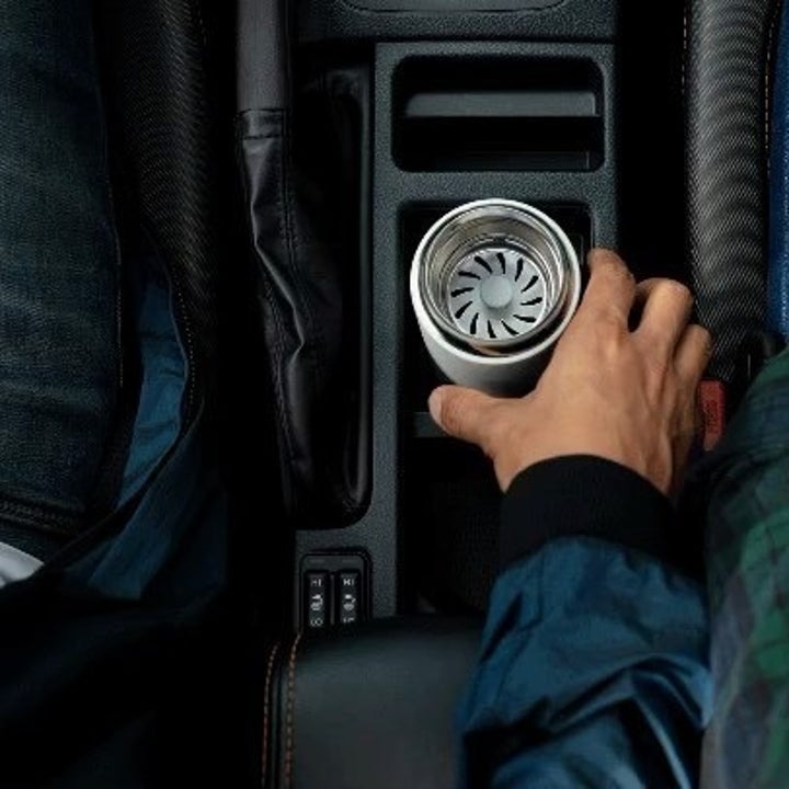 a person reaching for the tumbler in their cupholder