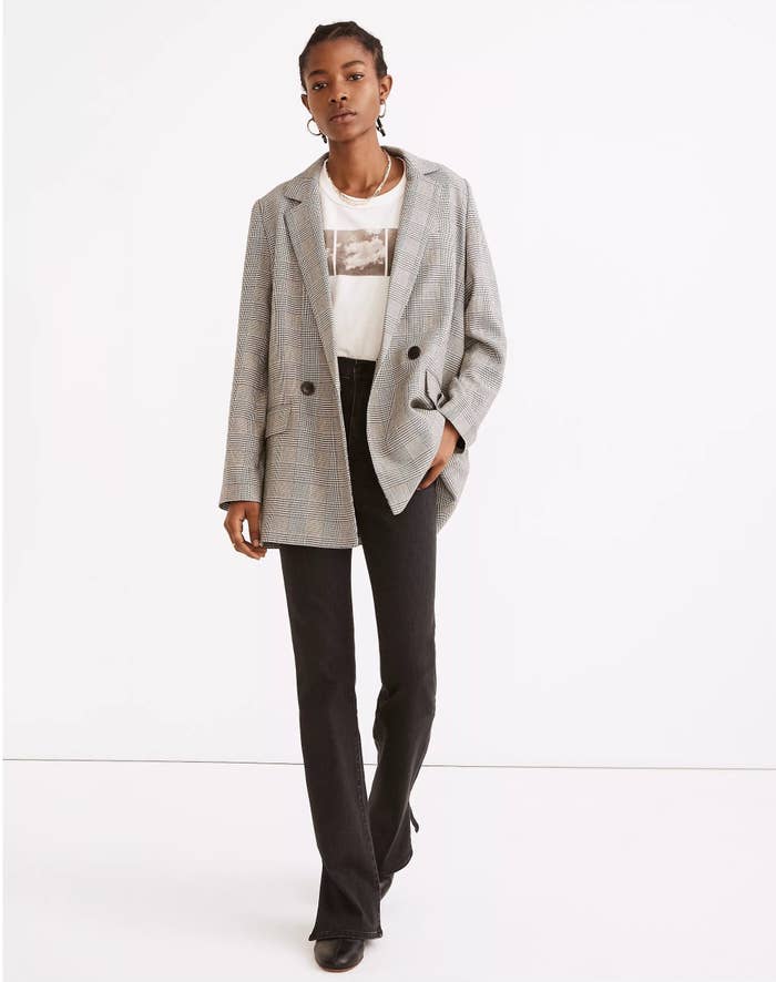 Model wearing grey blazer over white tee and black jeans