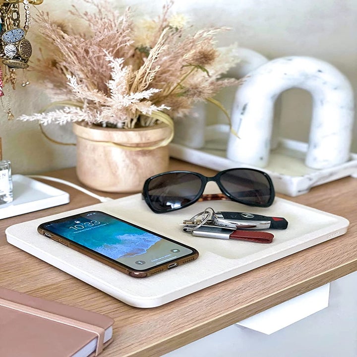 a reviewer shows their charging station with a phone, sunglasses, and keys on top