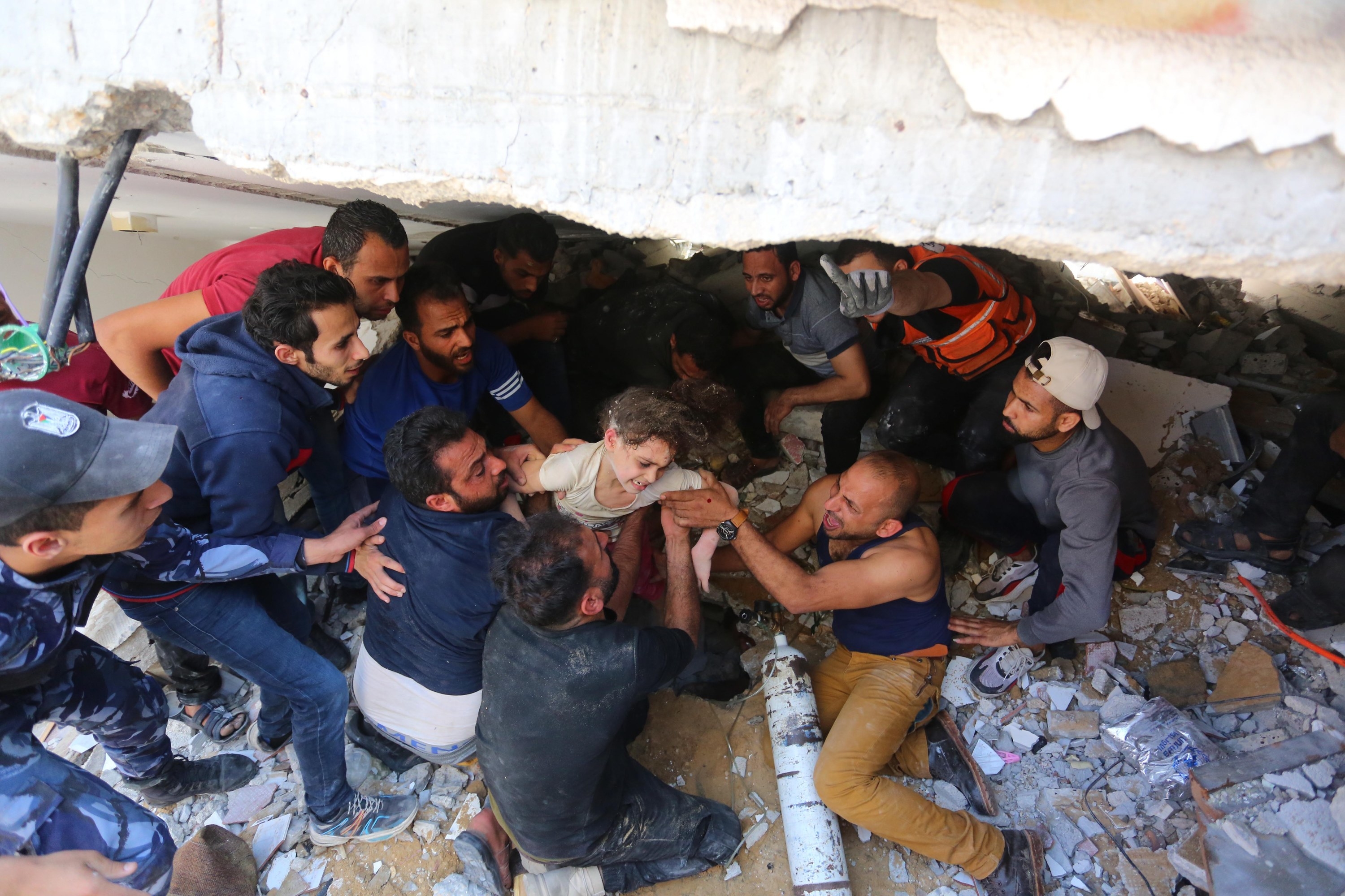 A young girl is pulled out of rubble by a group of men after a bombing in Gaza