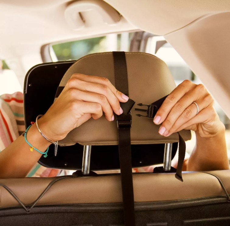 An image of a person fastening on in-sight adjustable car mirror onto a car seat