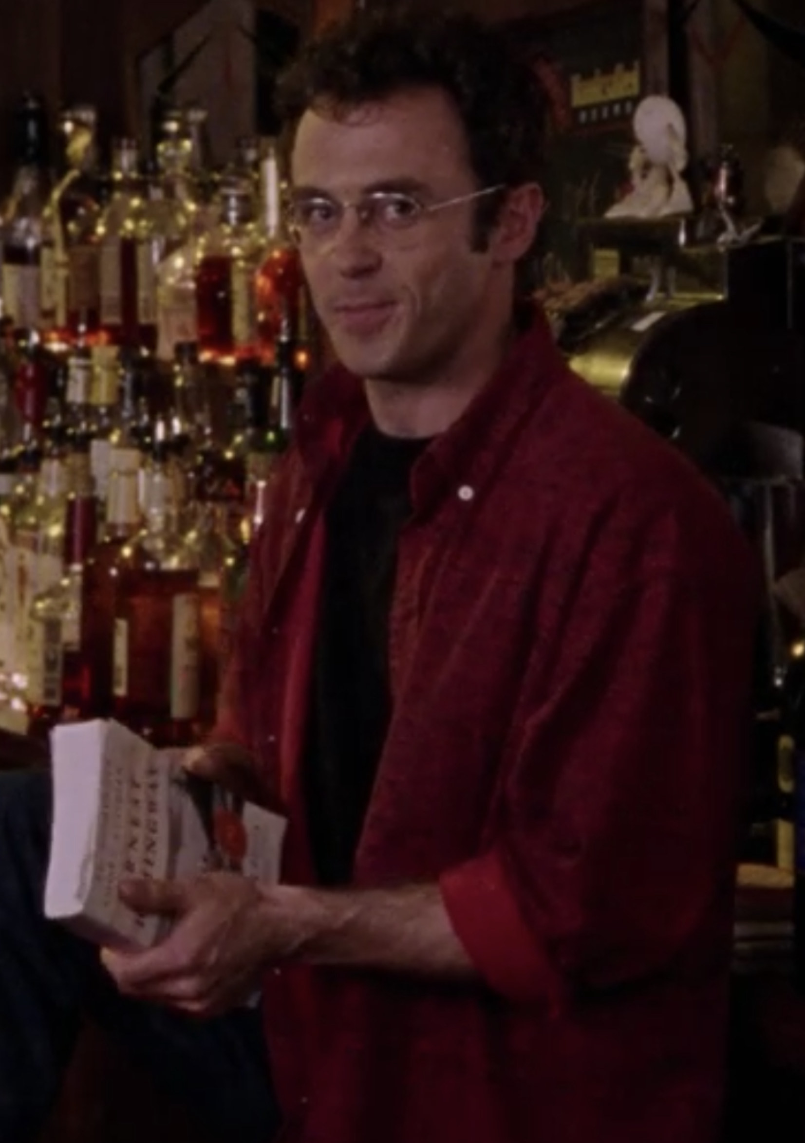 Eigenberg smirking at Cynthia Nixon while holding a book in a bar