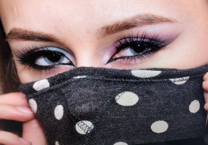 A woman with a full smoky eye makeup look with a mask covering the bottom half of her face