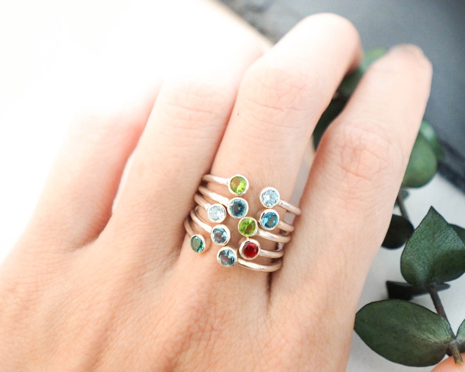 A person wearing a range of birthstone rings.