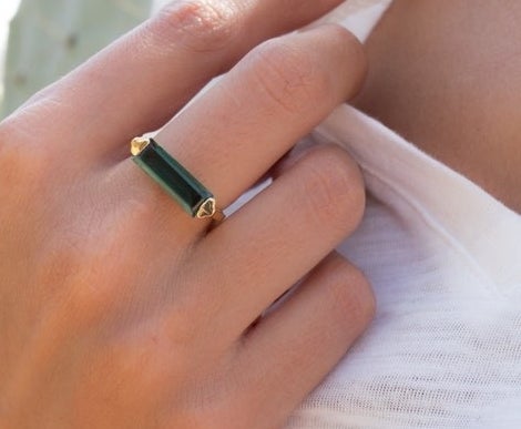 A person wearing a rectangular green stone ring.