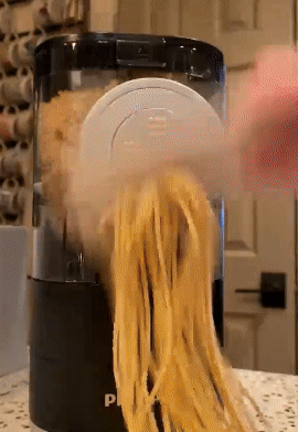 GIF of reviewer slicing pasta that's being extruded through the pasta maker