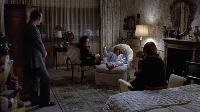 Regan sitting in a chair, hypnotized, with Chris and two doctors sitting around her in &quot;The Exorcist&quot; (1973)