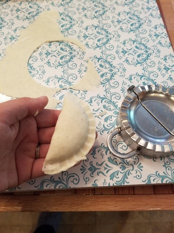 Reviewer holding handmade pierogi next to the dumpling press