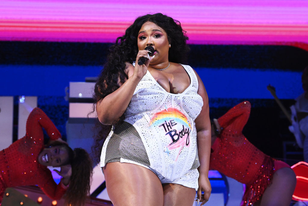 Lizzo performing on stage in a white body suit
