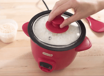 GIF of someone lifting the lid off the red rice cooker and revealing cooked white rice, followed by a spatula being used to scoop up rice