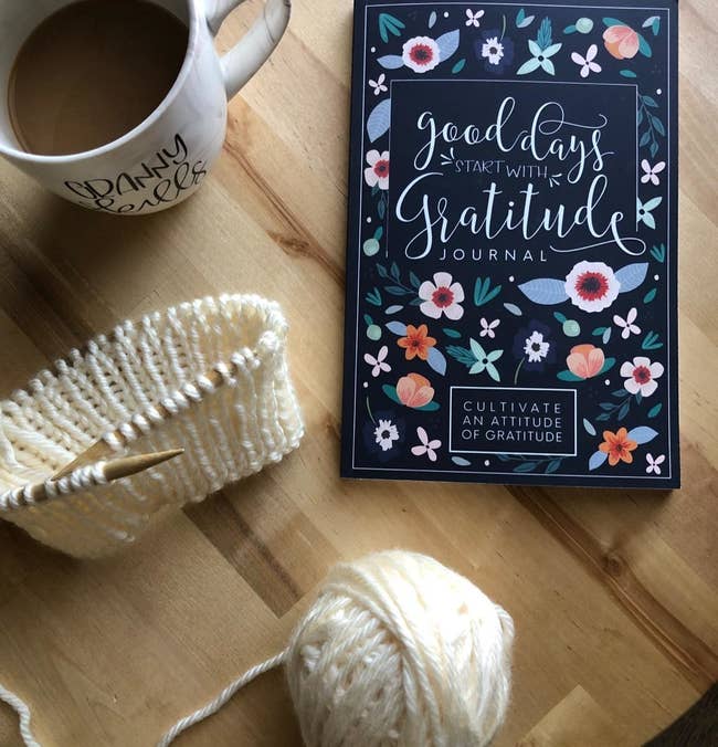 a reviewer shows the cover of the journal laying on a table beside coffee and knitting needles