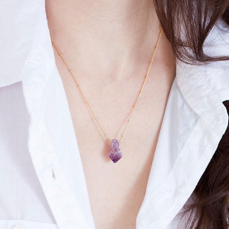 A person wearing an amethyst necklace.