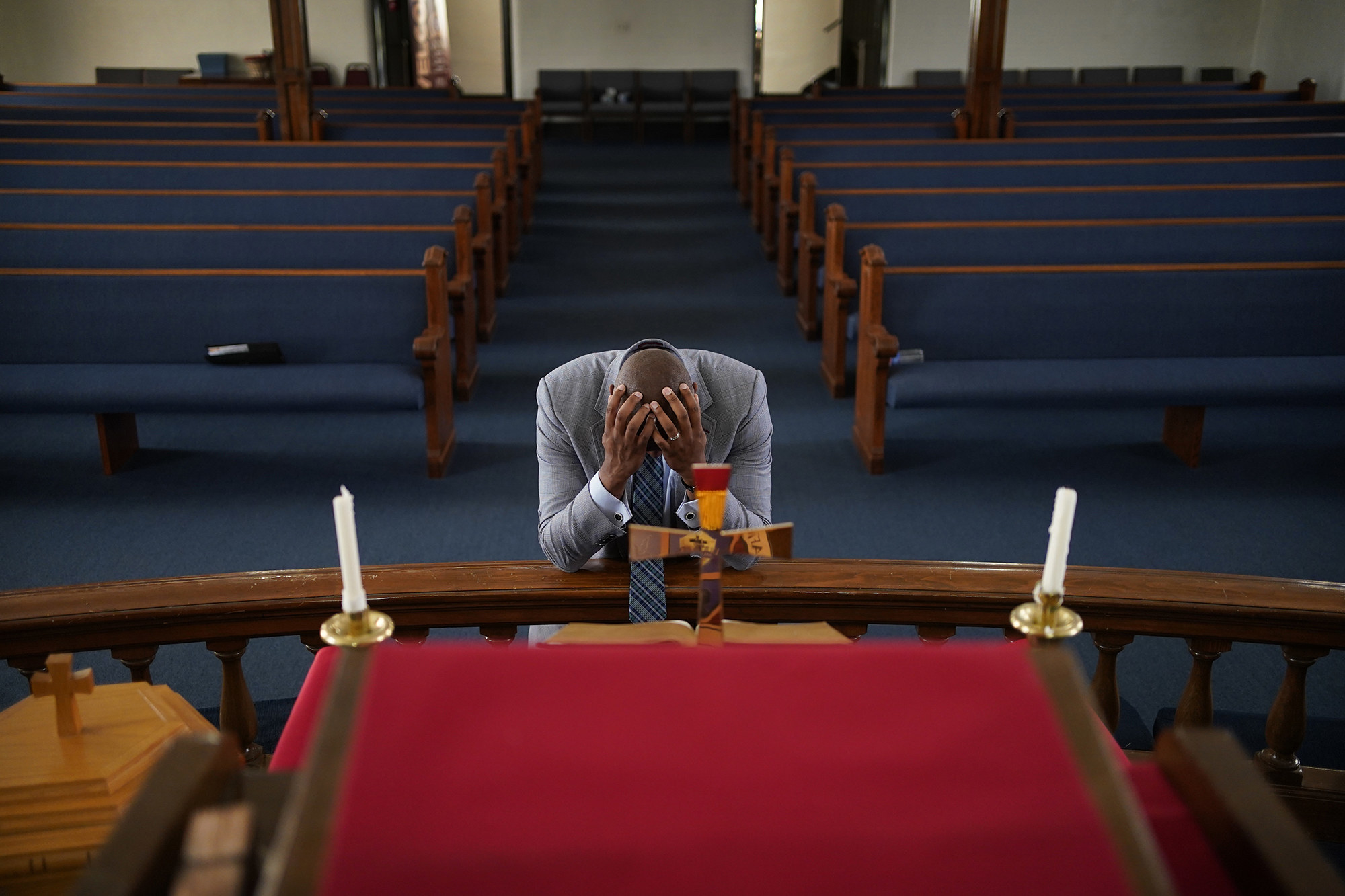 A man buries his face in his hands while kneeling at an altar