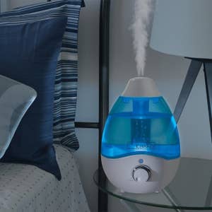 blue droplet-shaped humidifier emitting steam on bedside table