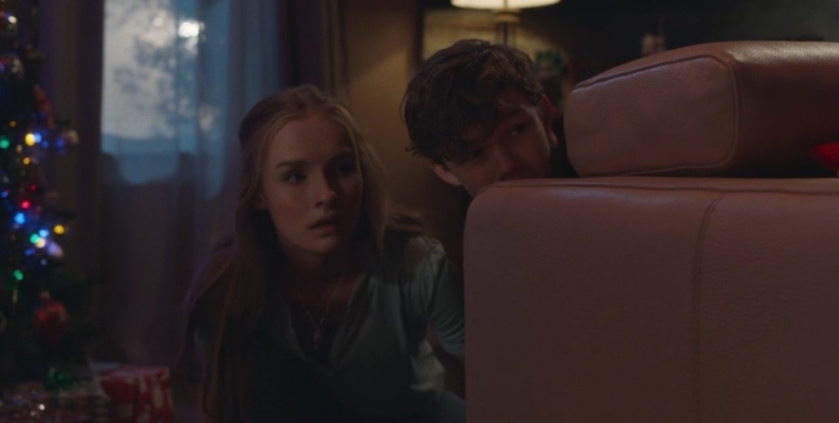 Ashley (Olivia DeJonge) and Luke (Levi Miller) hide behind a couch in &quot;Better Watch Out&quot;