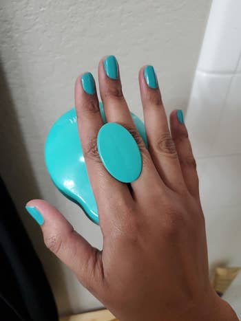 Reviewer holding the teal brush and showing the handle in their hand
