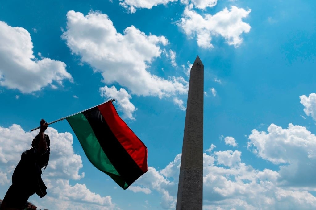 A woman waving the Pan-African flag in front of the Washington Monument