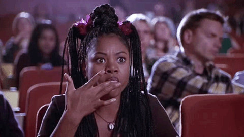 Regina Hall in a movie theater, watches a scary movie playing with wide eyes