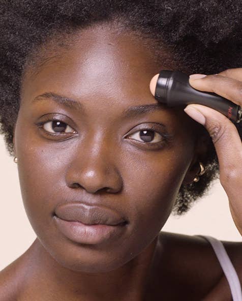 A person using the oil-absorbing roller on their forehead