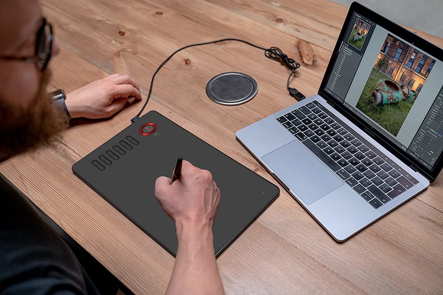 a person using the drawing tablet in front of their laptop on a desk