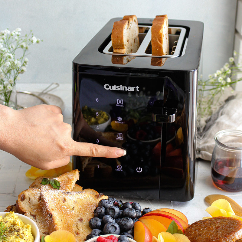 A person pressing the touchscreen on the Cuisinart toaster