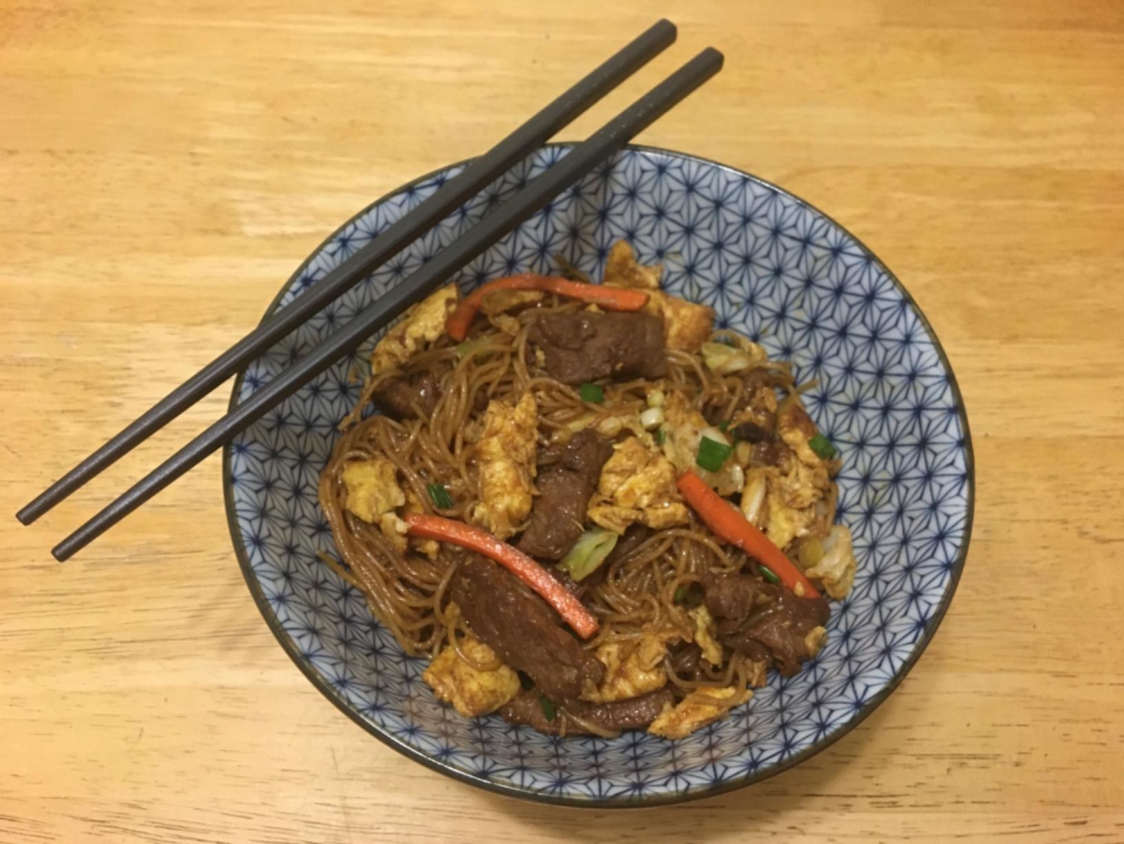reviewer&#x27;s black chopsticks resting on a bowl of noodles