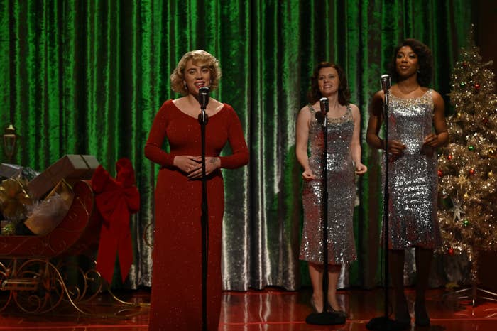 Billie singing on a Christmas-themed stage with two backup singers as part of a sketch