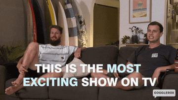 Gif shows two men sitting on a sofa one gestures to the TV and says this is the most exciting show on TV