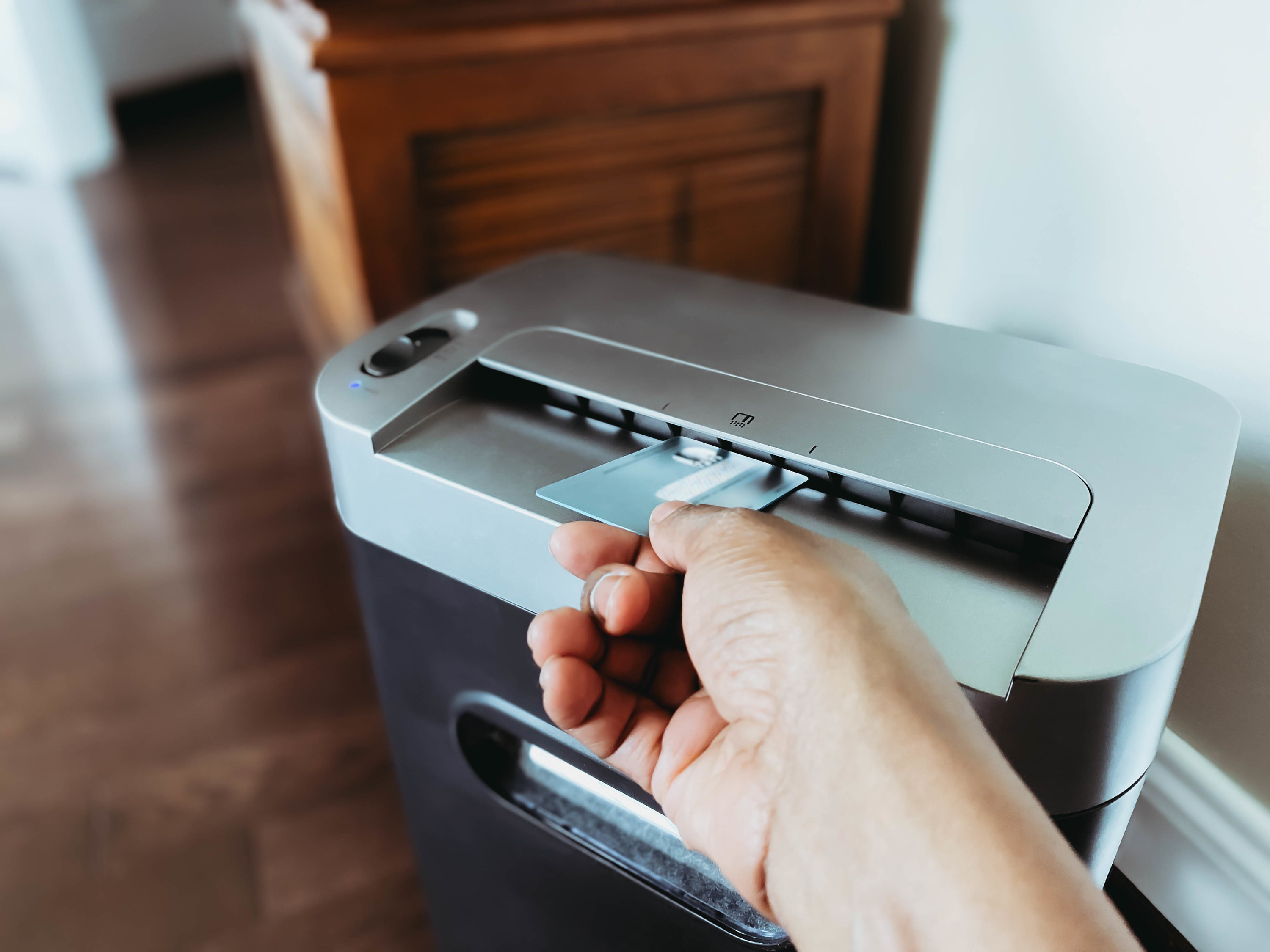 Close-up of hand putting a credit card into a paper shredder