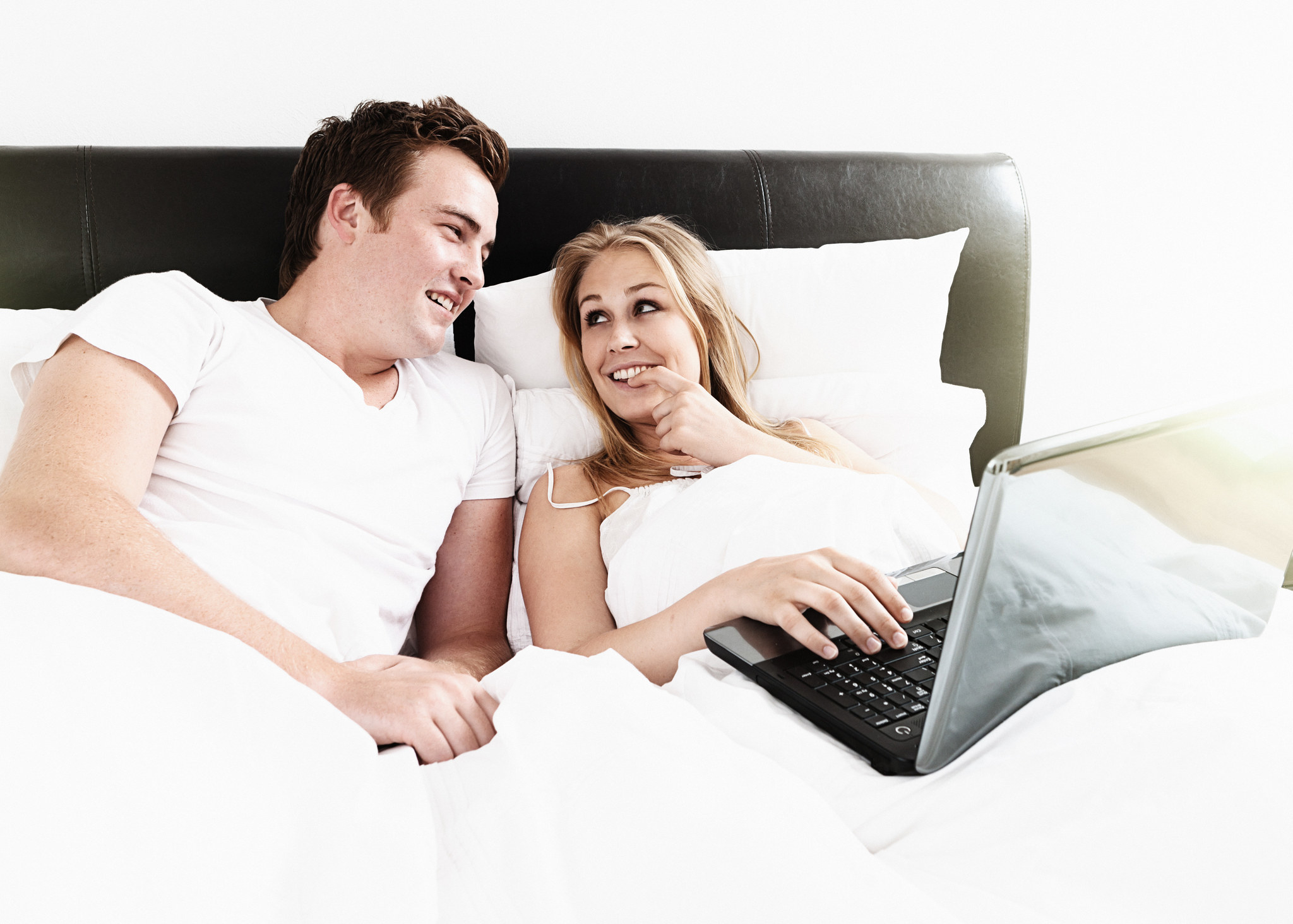 A couple looking mischievously at a laptop