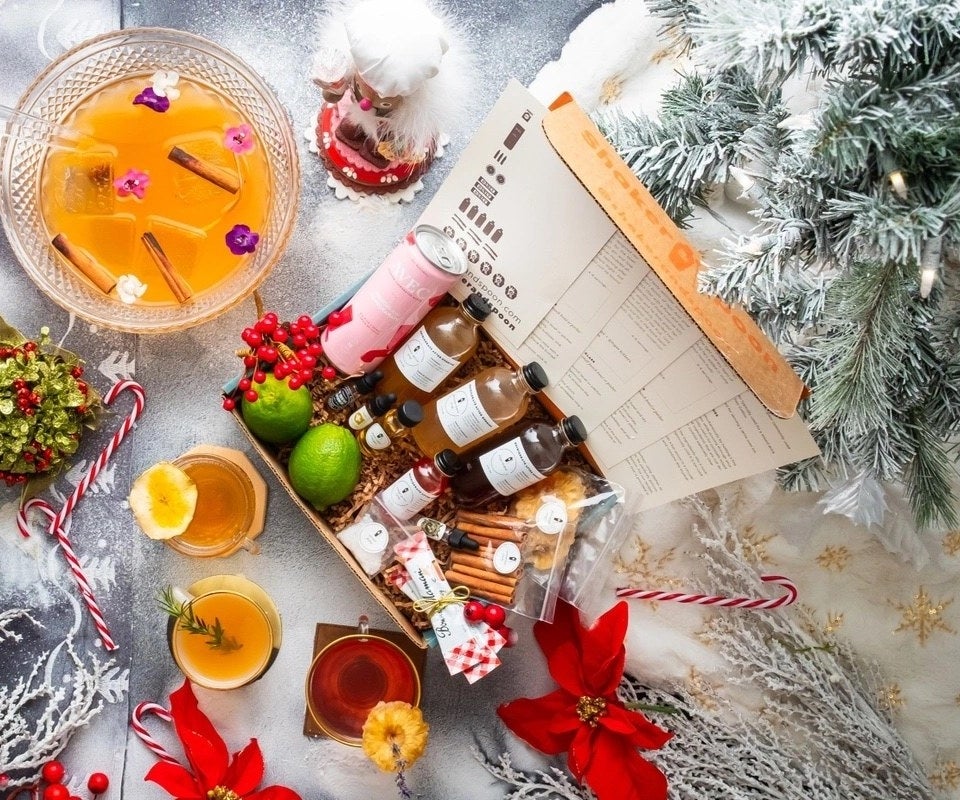 The cocktail club subscription box featuring cocktail ingredients surrounded by festive holiday decor and a punch bowl